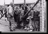 Women and children survivors in Mauthausen speak to an American liberator through a barbed wire fence. * 480 x 333 * (67KB)